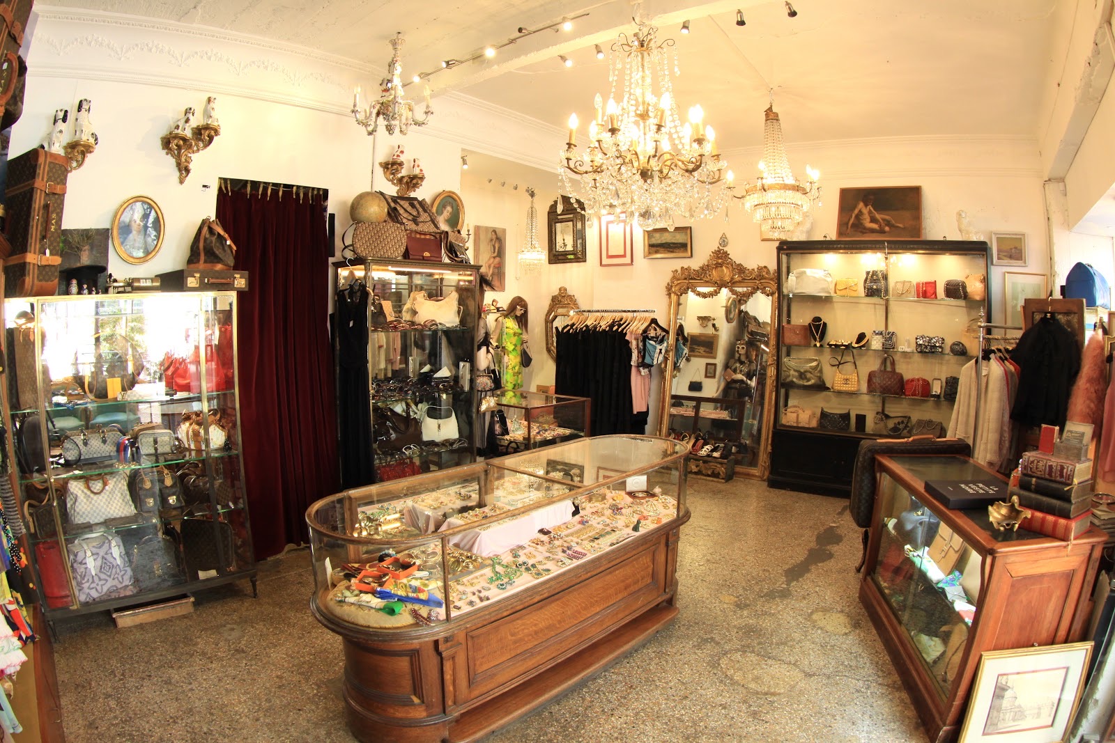Intérieur de la boutique MADEMOISELLE à Nice : lustres anciens, vitrines de sacs de créateurs et comptoir de bijoux