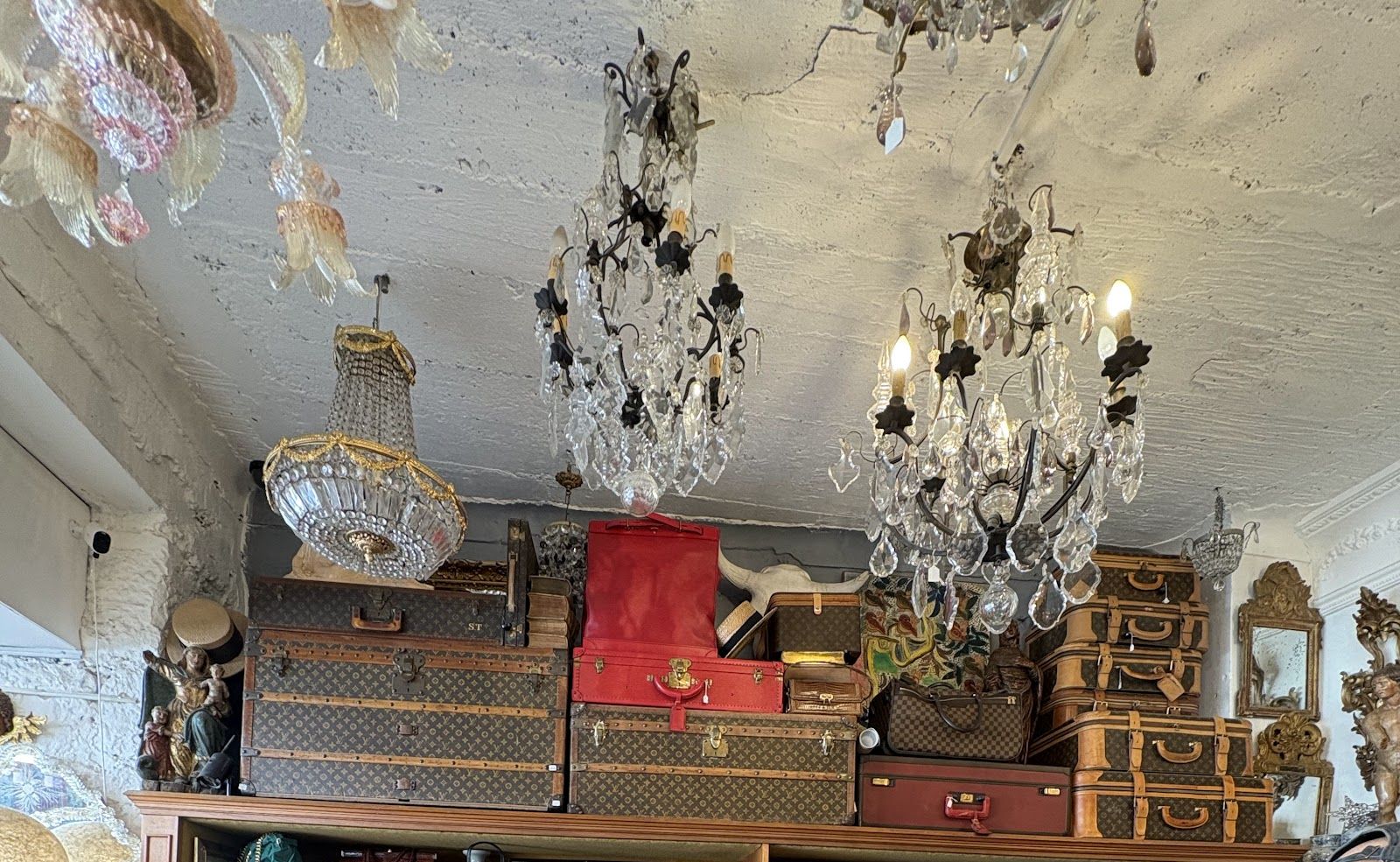 Malles et valises Louis Vuitton anciennes sous les lustres à pampilles